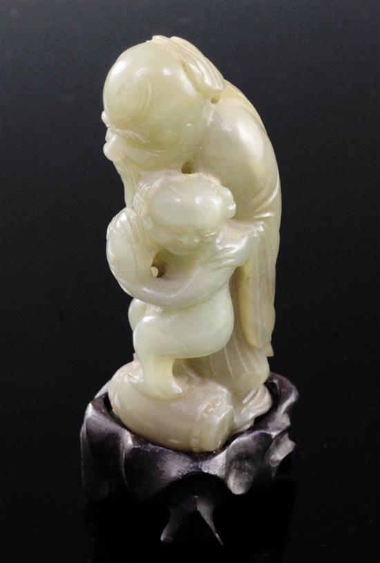 A Chinese celadon and brown jade group of Shou Lao and a boy standing upon a barrel, 18th/19th century, 7.3cm, ebonised wood stand